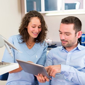 A cosmetic dentist in Loves Park showing smile makeover options to a patient