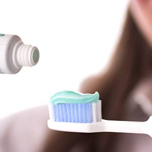 Lady applies toothpaste to brush