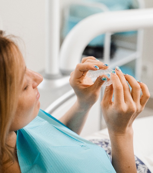 Patient holding clear aligner in treatment room