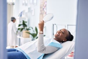 happy patient lying down in the dental chair smiling into a mirror