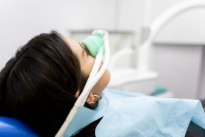 Woman being sedated in dentist’s chair with gas mask.
